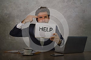 Depressed and stressed attractive hispanic man in suit and tie working overwhelmed office computer desk holding notepad asking for