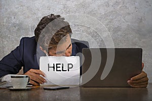 Depressed and stressed attractive hispanic man in suit and tie working overwhelmed office computer desk holding notepad asking for