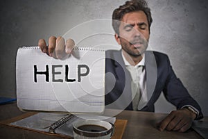 Depressed and stressed attractive hispanic man in suit and tie working overwhelmed office computer desk holding notepad asking for