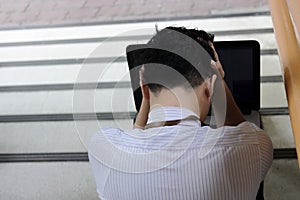 Depressed stressed young Asian business man covering face with his hands and feeling tired and exhausted.