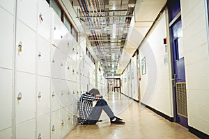 Depressed student sitting in locker room