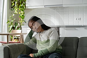 Depressed suffering Asian woman sitting on sofa with head down needs to take antidepressants