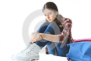 depressed teen girl sitting near backpack alone