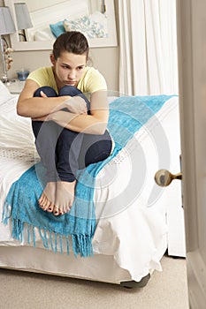 Depressed Teenage Girl Sitting On Bed