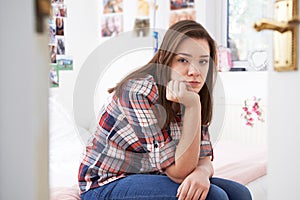 Depressed Teenage Girl Sitting In Bedroom