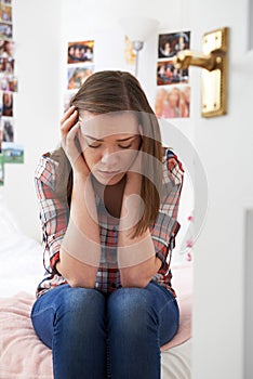 Depressed Teenage Girl Sitting In Bedroom