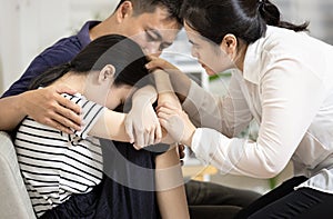 Depressed teenager girl with depressive symptoms,depression disease,feels sad crying,asian mom and dad hugging embracing daughter