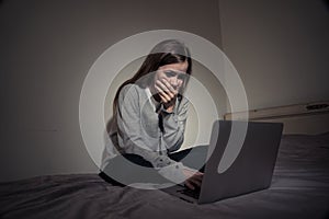 Depressed teenager girl with laptop suffering bullying and harassment online. Cyberbullying concept