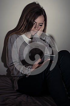 Depressed teenager girl on mobile phone victim of cyberbullying feeling sad, unhappy and lonely