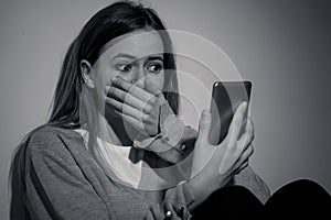 Depressed teenager girl on mobile phone victim of cyberbullying feeling sad, unhappy and lonely