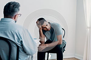 Depressed teenager looking away while talking to his therapist