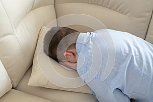 Depressed teenager lying face down on sofa