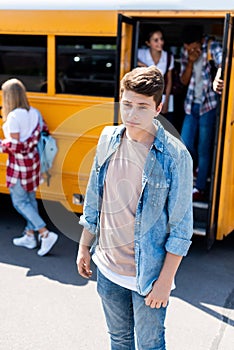 depressed teenager schoolboy standing in front of school bus