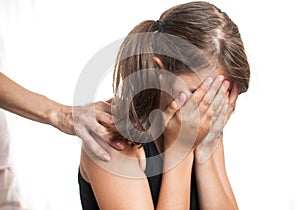 Depressed teenager sitting while hand coming from behind photo