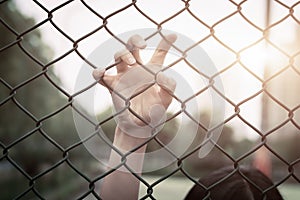 Depressed, trouble, help and chance. Hopeless women raise hand on chain-link fence ask for help