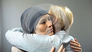 Depressed woman in headscarf hugging her mother, cancer treatment, diagnosis