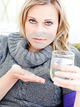 Depressed woman holding pills and water at home