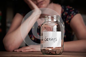 Depressed Woman Looking At Empty Jar Labelled Savings photo