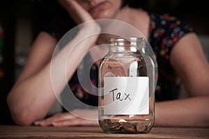 Depressed Woman Looking At Empty Jar Labelled Tax