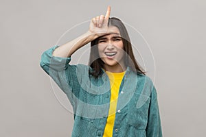 Depressed woman showing loser gesture, L finger sign on forehead, upset about dismissal, unlucky day