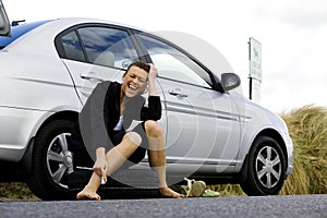 Depressed woman sitting at her broken car