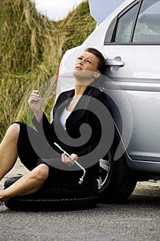Depressed woman sitting at her broken car