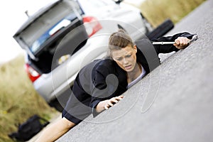 Depressed woman sitting at her broken car