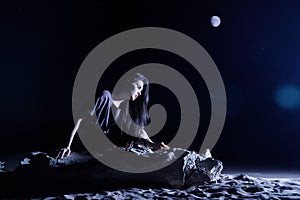 Depressed woman sitting on a stone in dark night. loneliness, sad, emotion concept