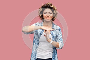 Depressed woman standing showing time out gesture, looking at camera, expressing sadness.