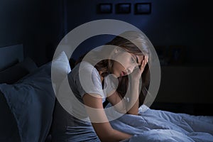 Depressed young Asian woman sitting in bed cannot sleep from insomnia