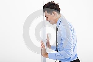 Depressed young business man leaning at the wall in office