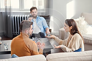 Depressed young couple of man and woman speaking with psychologist on therapy session in modern office. Bad