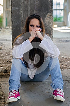 Depressed young girl sitting in the abandoned building