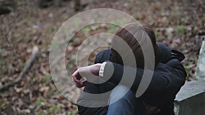 Depressed young man crying alone in park, having hysterics over troubles in life