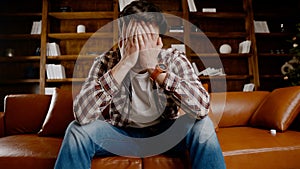 Depressed young man drinking alcohol at home. Unemployed male, drunk and continues drink wine straight bottle on couch near