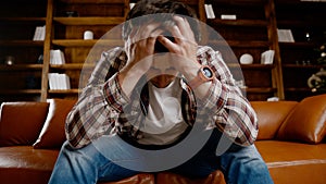 Depressed young man drinking alcohol at home. Unemployed male, drunk and continues drink wine straight bottle on couch near