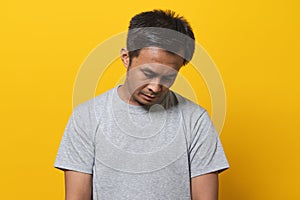 Depressed young man face down feeling failure. Shot in studio isolated on yellow background