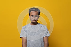 Depressed young man face down feeling failure. Shot in studio isolated on yellow background