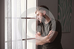 Depressed young man near window