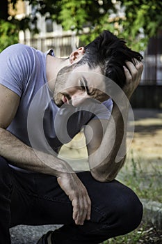 Depressed young man scratching his head, looking up