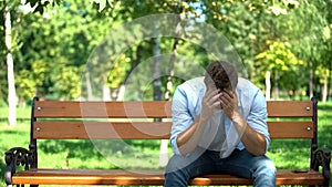 Depressed young man sitting alone bench thinking problem, broken heart, crisis
