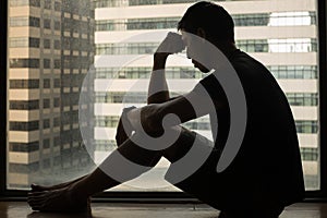 Depressed young man sitting alone at home in apartment. Sad people