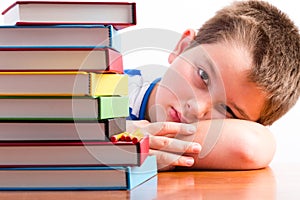 Depressed young schoolboy eyeing his textbooks photo