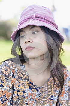 Depressed young woman bends down head sitting in the park. Outdoor portrait of a sad teenage girl looking thoughtful about
