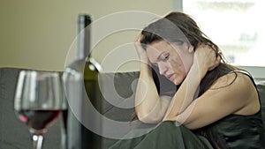 Depressed young woman crying - a victim of domestic violence or abuse tries to relieve suffering with alcohol. Domestic