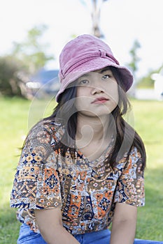 Depressed young woman looking at camera sitting in the park. Outdoor portrait of a sad teenage girl looking thoughtful about