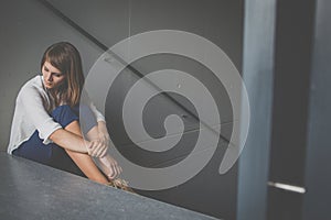 Depressed young woman sitting in a staircase, jobloss due to coronavirus pandemic