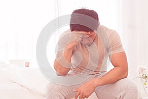 Depressing man is siting on bed with headache