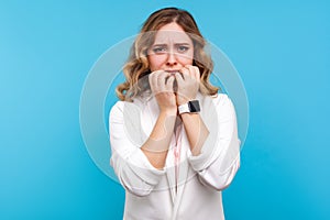 Depression and anxiety. Portrait of worried woman biting nails looking frightened terrified about problems. blue background