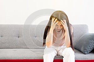 Depression asian woman have a headache or migraine of lonely sitting on sofa at home,Female under a lot of pressure,Mental health